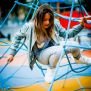 فتاة تتسلق شبكة Powerclimber climbing net الزرقاء في ملعب للأطفال.